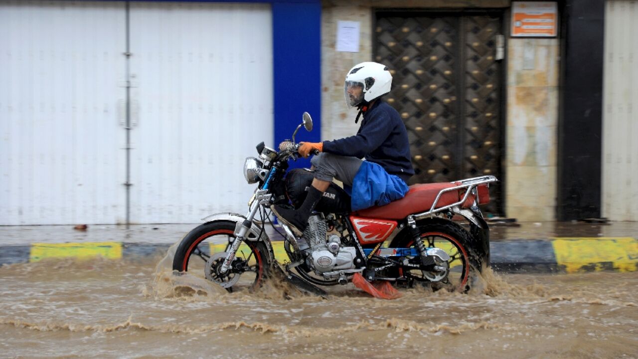 A man rides a motorcycles on a flooded street amid heavy rainfall in Yemen's capital Sanaa, which is controlled by Huthi rebels, on March 31, 2023