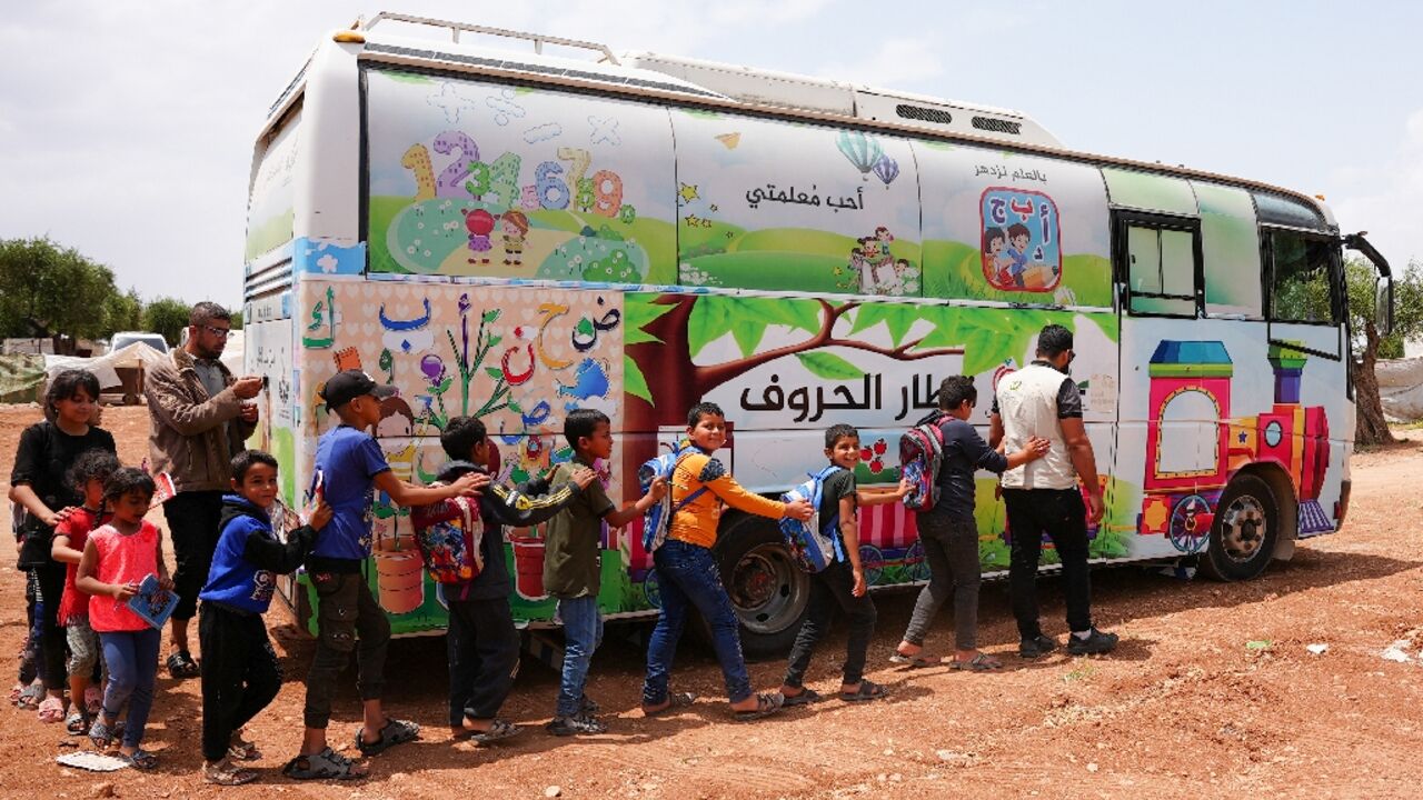 Pupils board a bus turned into a travelling classroom in northwest Syria