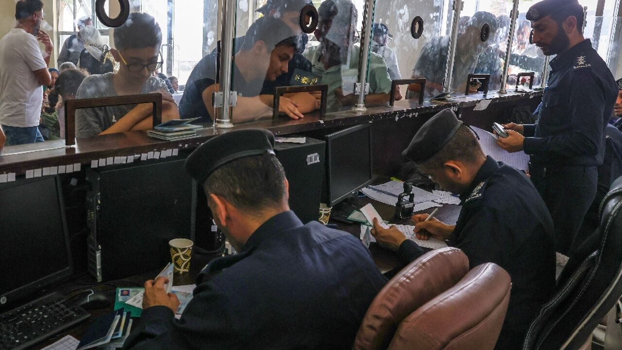 Civilians leaving Gaza display their documents as dual national Palestinians and foreigners prepare to cross the Rafah border with Egypt