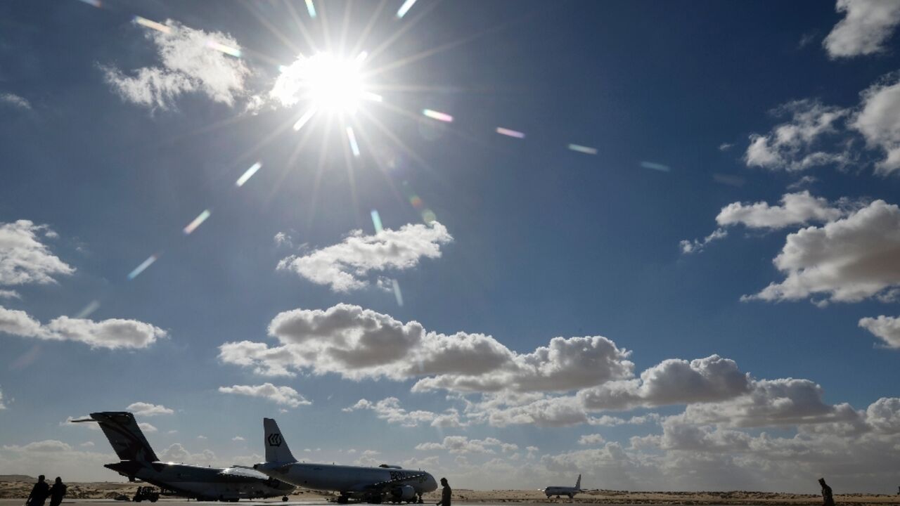 Staff members walk past airplanes bringing aid for the Gaza Strip on the tarmac of Egypt's El-Arish airport on November 27, 2023