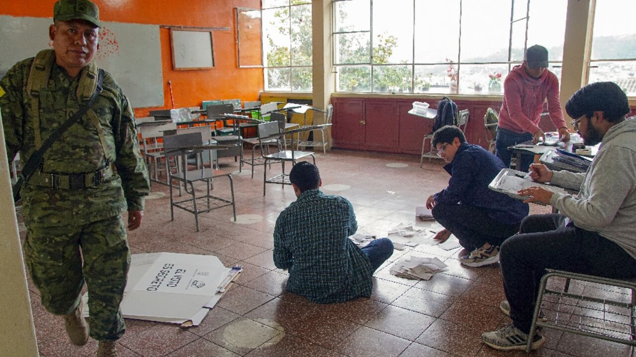 Electoral workers examine ballots while counting votes at a polling station in Cuenca, Ecuador, on October 15, 2023