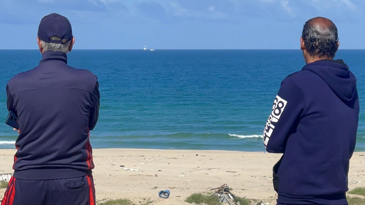 Palestinian men watch the Open Arms charity vessel bringing the first shipment of food aid to Gaza via a new maritime corridor from Cyprus