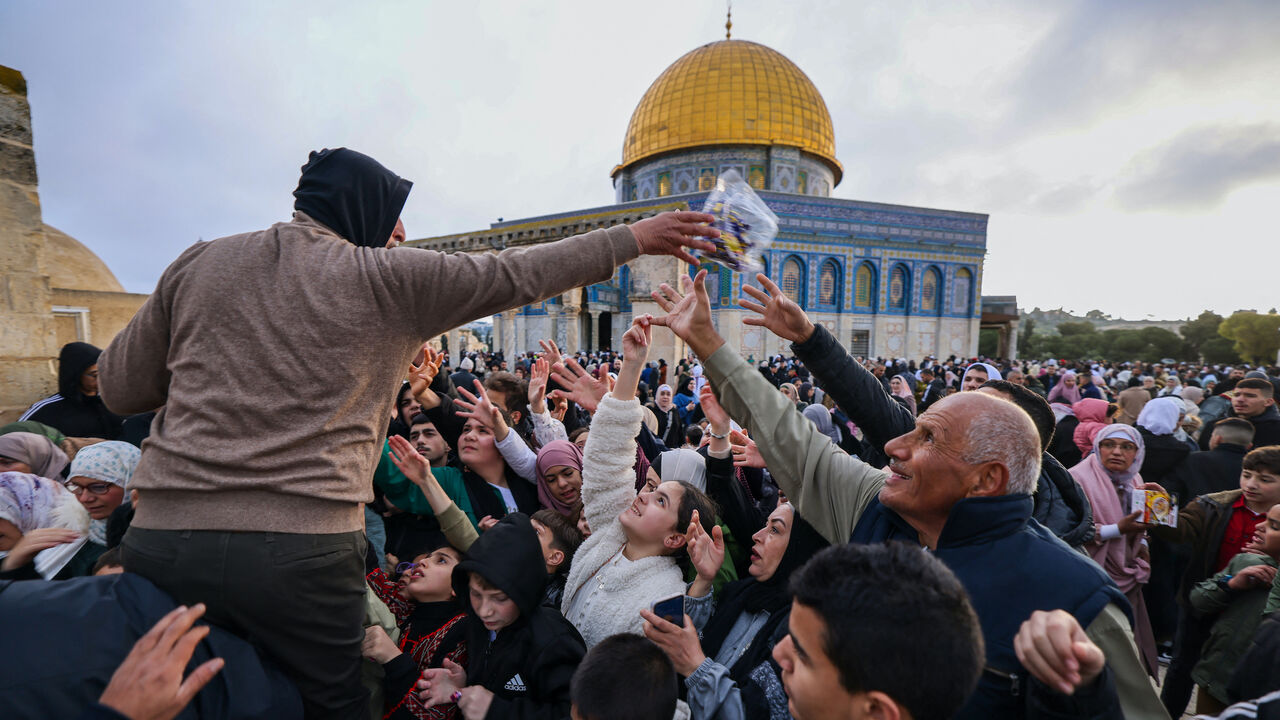 A volunteer distributes sweets to Muslims after special morning prayers to start the Eid al-Fitr festival, which marks the end of the holy fasting month of Ramadan, at the Al-Aqsa Mosque compound in Jerusalem on April 10, 2024.
