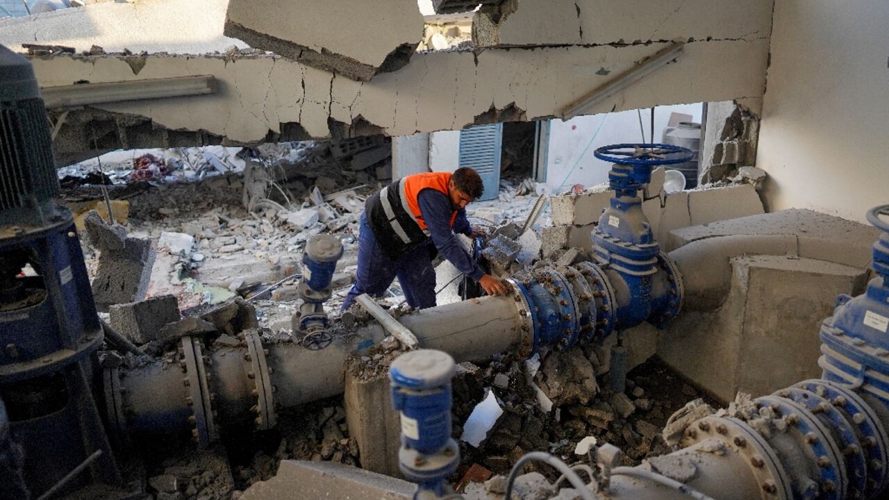 A Palestinian worker checks a pipe at a municipal water management facility that was hit during a strike in Nuseirat, central Gaza