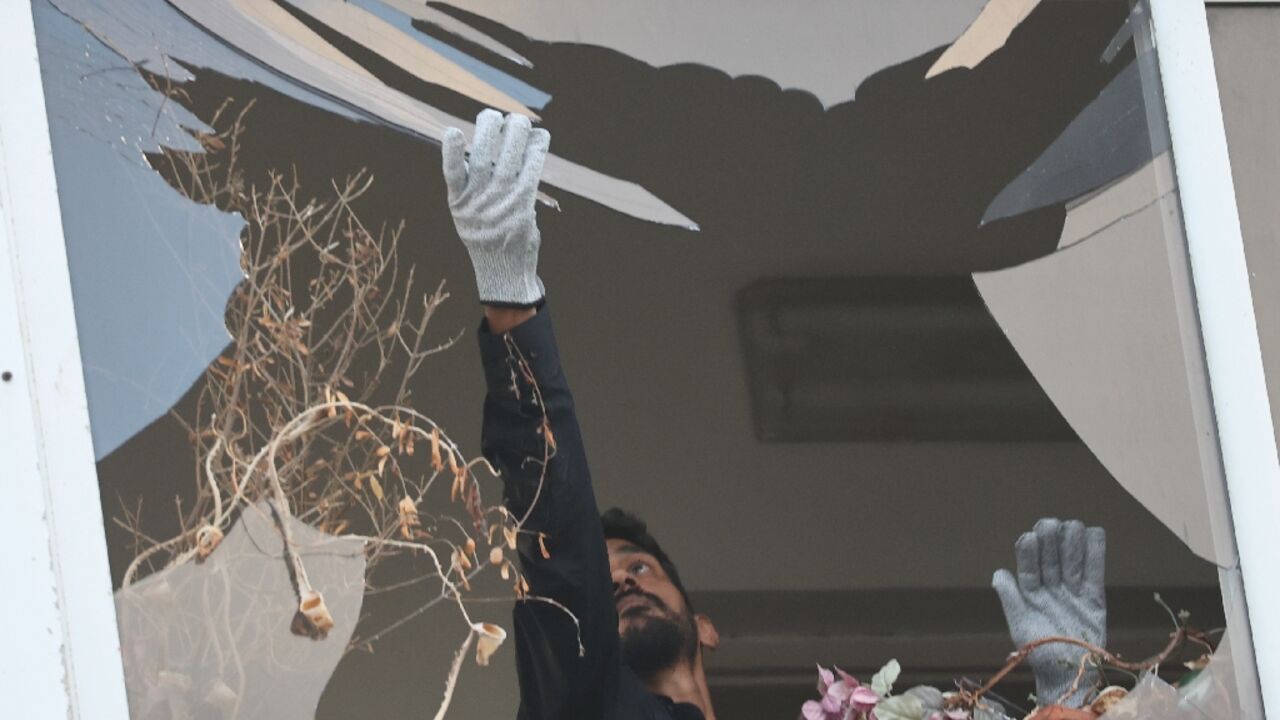 An Israeli policeman collects glass shrapnel from the window of a building that was damaged in an explosion in Tel Aviv