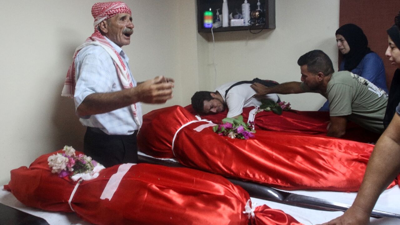 Relatives mourn over the bodies of four members of one family killed in the air strike