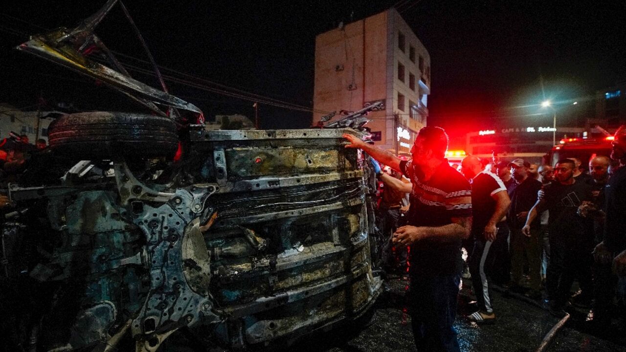 First responders gather around a car hit by an Israeli drone strike in the occupied West Bank city of Jenin