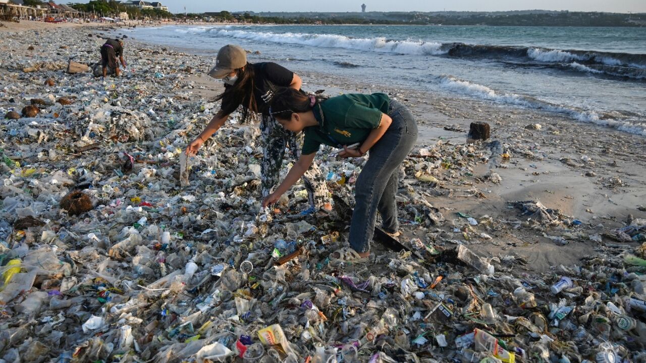 People look through plastic and other debris washed ashore at a beach on Indonesia's resort island of Bali