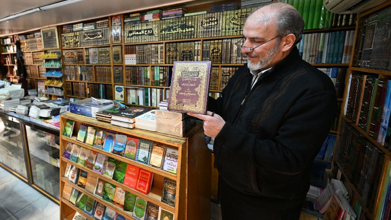 A bookseller shows a volume that was reportedly banned during the rule of Syria's ousted president Bashar al-Assad