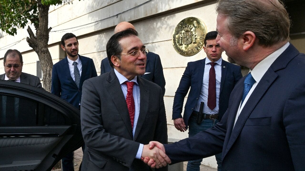 Spain's Foreign Minister Jose Manuel Albares (L) shakes hands with an official outside Madrid's reopened embassy in Damascus