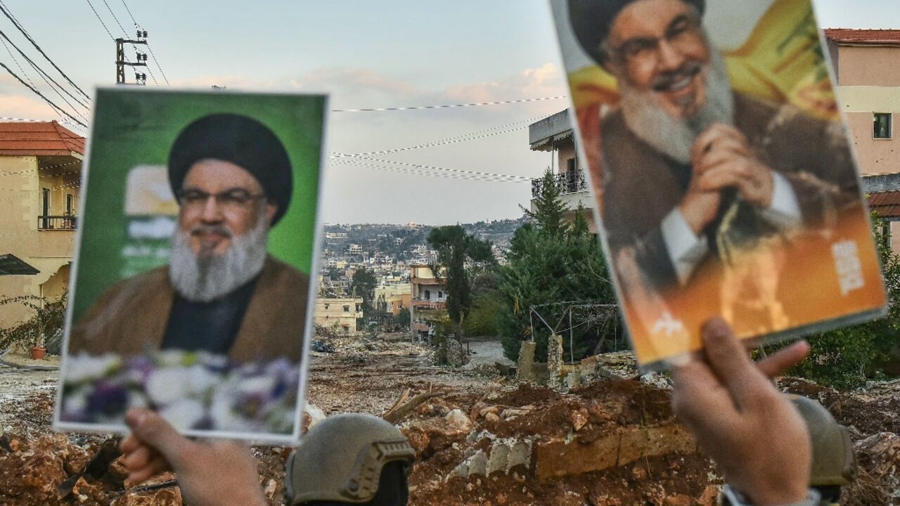 Residents of the southern Lebanese village of Aitaroun lift portraits of Hezbollah's slain leader Hassan Nasrallah as Lebanese army soldiers prevent them from entering their town while an Israeli tanks blocks the road ahead