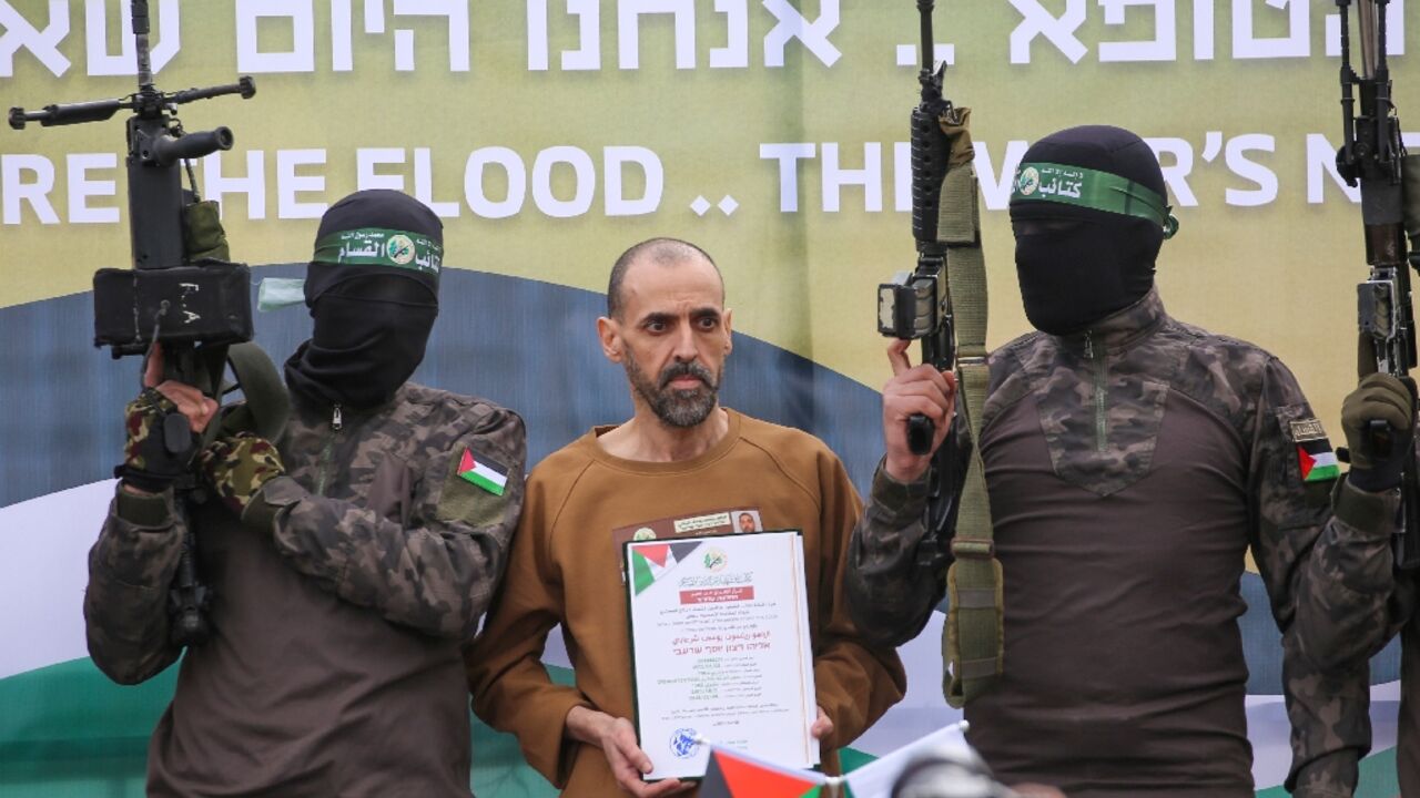 Hamas fighters escort Israeli hostage Eli Sharabi on a stage before handing him over to a Red Cross team in Deir el-Balah, central Gaza, on February 8, 2025 under a truce deal
