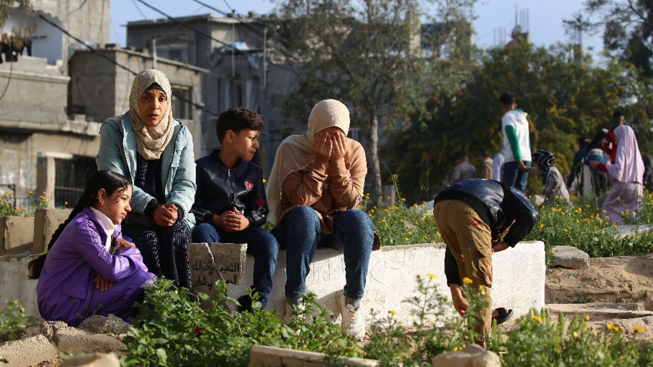 Palestinians visit the grave of a relative after Eid al-Fitr prayers, in the central Gaza Strip