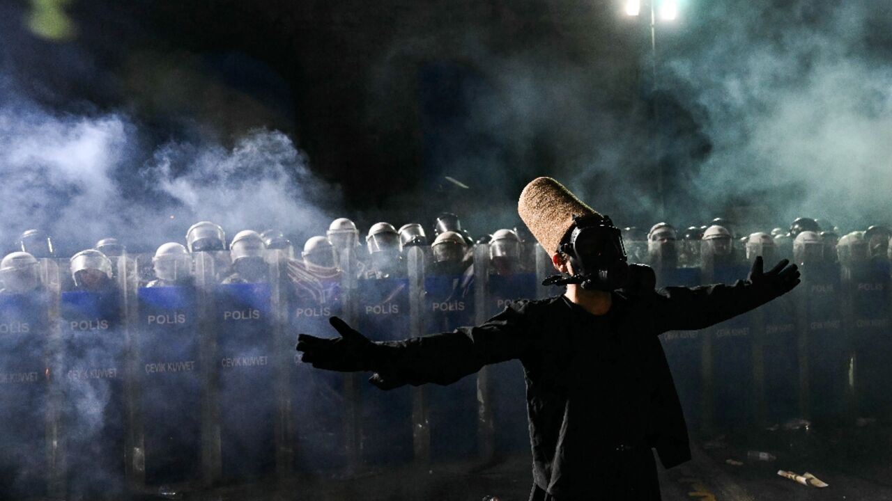 A whirling dervish stands in of front riot police in Istanbul 
