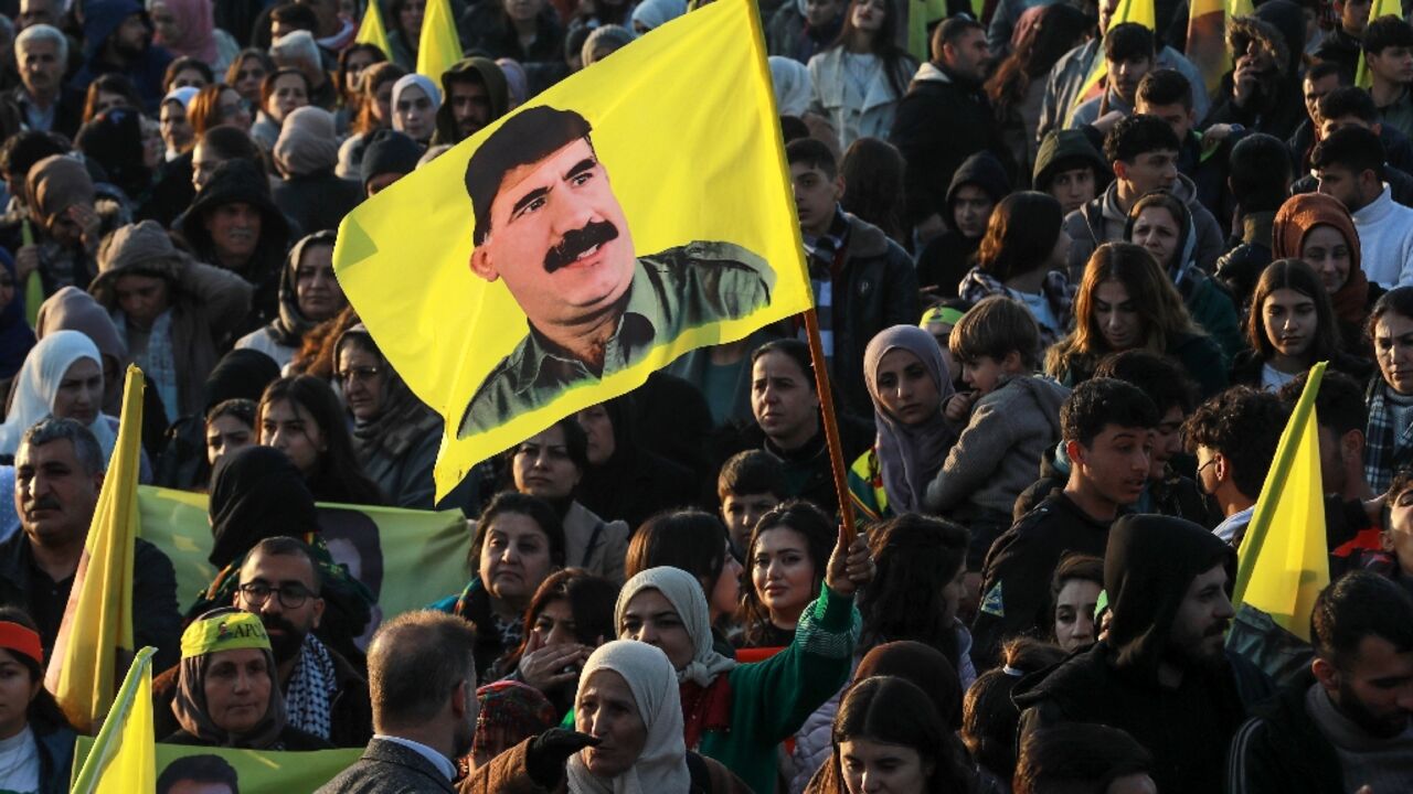 A woman waves a flag bearing a picture of PKK founder Abdullah Ocalan