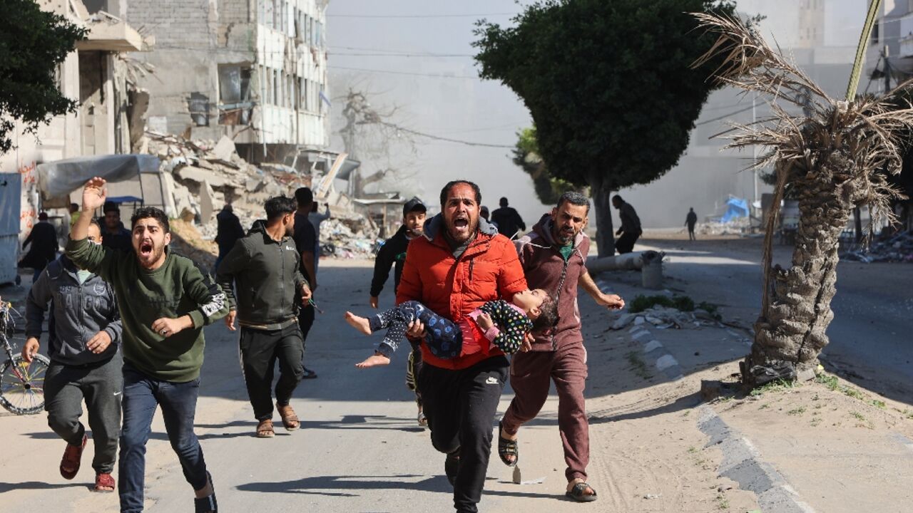 Palestinians rush an injured girl away from the site of Israeli strikes on a makeshift displacement camp in Gaza City 