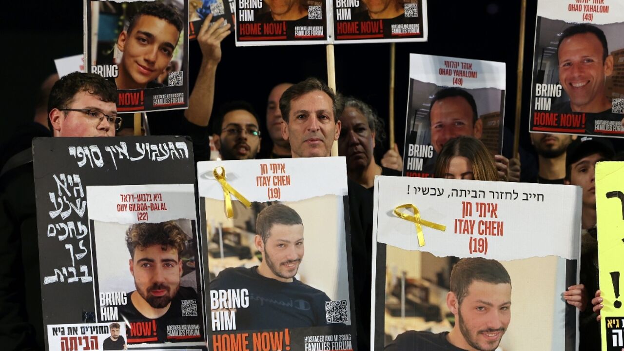 Relatives and supporters hold portraits of Israeli hostages, including Guy Gilboa-Dalal, pictured bottom left