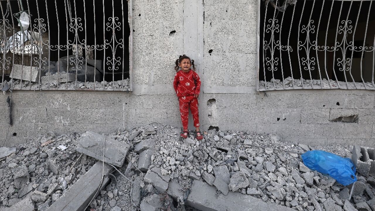 A crying Palestinian girl stands over the debris of a house hit by an Israeli strike in the south Gaza city of Khan Yunis on Wednesday.