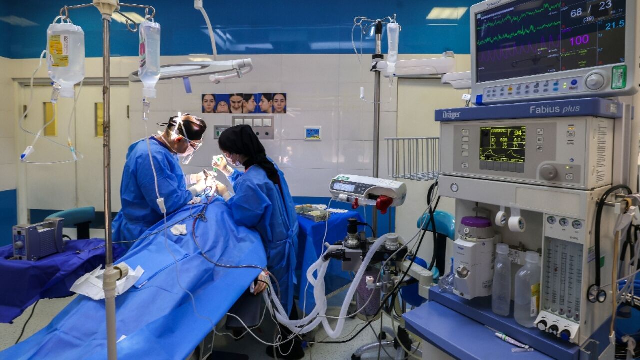 Iranian surgeon Hamidreza Hosnani and an assistant perform surgery at his private clinic in Tehran