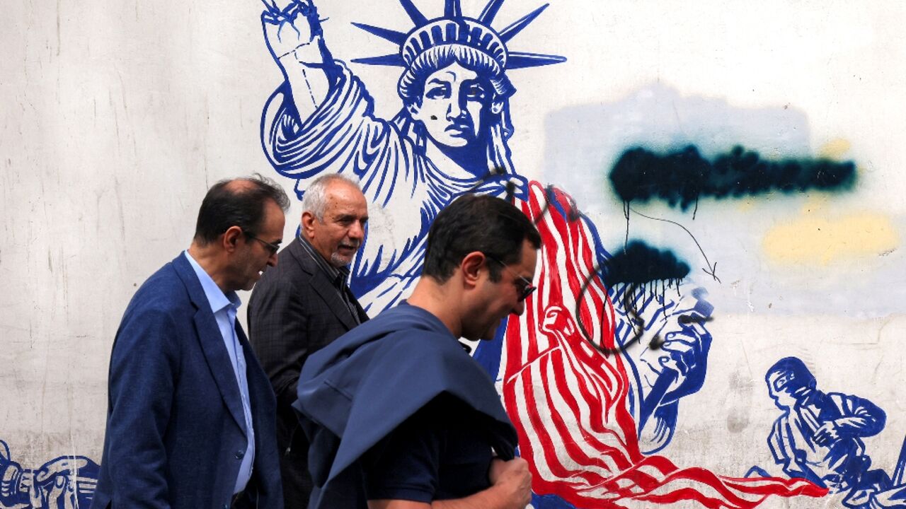 Iranian walk past a mural on the walls of the former US embassy building in Tehran, dubbed the "Den of Spies" since the Islamic revolution of 1979.