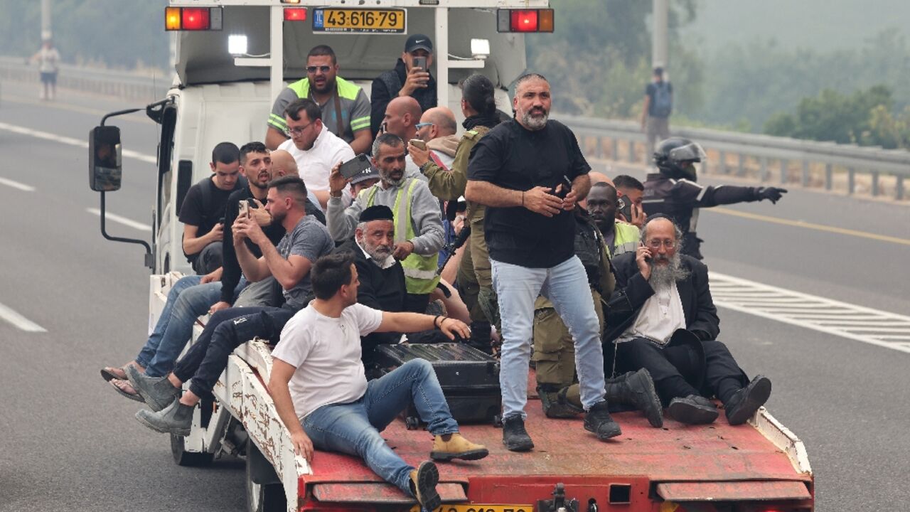 People are evacuated on a recovery vehicle at a highway during a forest fire 