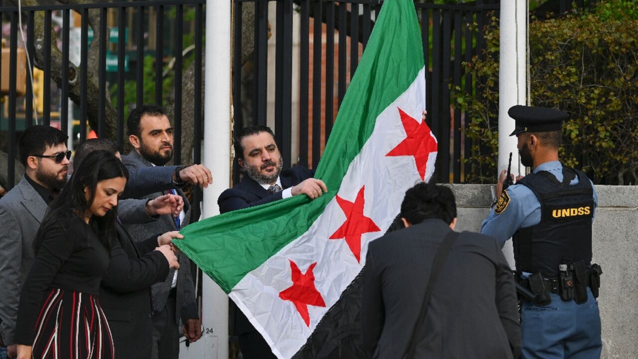 Syrian Foreign Minister Asaad al-Shaibani raises the new Syrian flag during a ceremony at United Nations headquarters in New York 