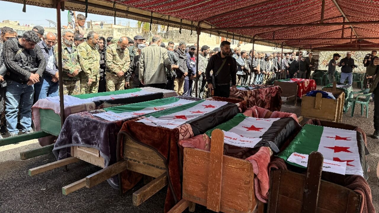 Mourners pray over the flag-draped coffins of people killed in reported Israeli shelling in Syria's southern province of Daraa