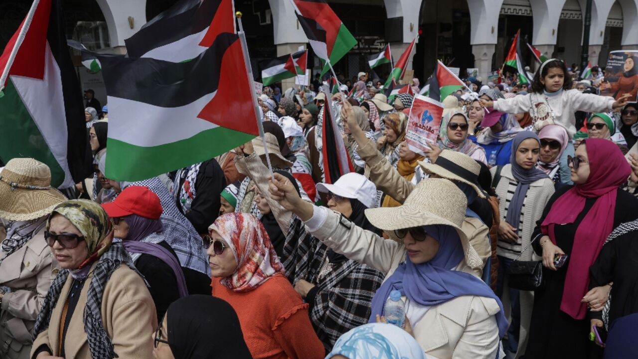 Protesters carry Palestinian flags and placards during the demonstration in Rabat