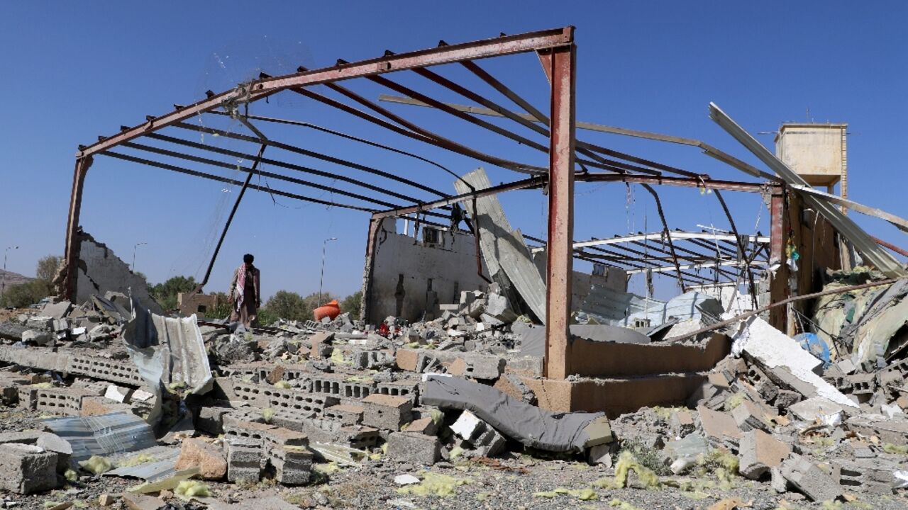 A man inspects the wreckage of a building destroyed in Yemen by a strike on a migrant centre attributed to the US