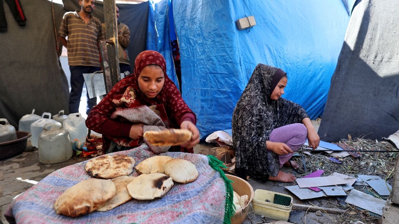 Displaced Palestinian girls bake bread at the Bureij refugee camp in the central Gaza Strip 