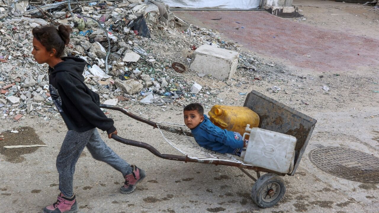 Palestinian children head to a water distribution point to fill their containers in Gaza City