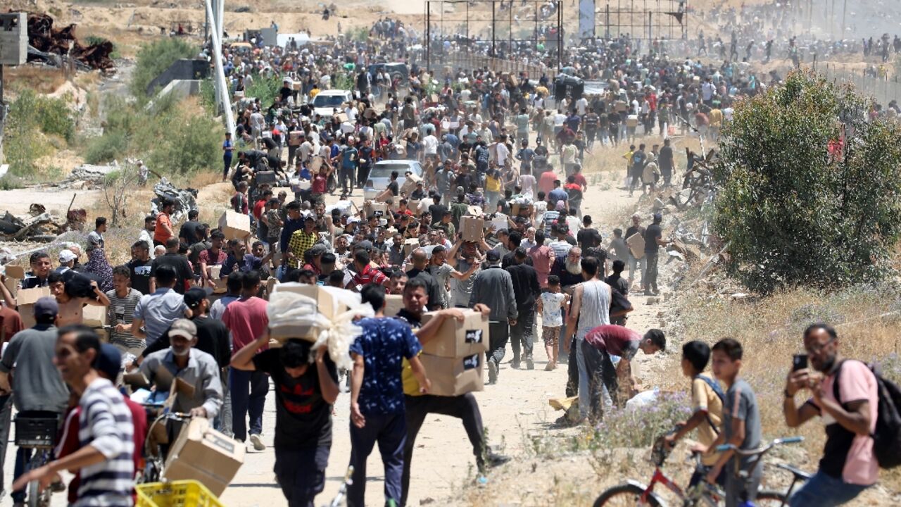 People carry boxes of relief supplies from the Gaza Humanitarian Foundation at adistribution center in the central Gaza Strip