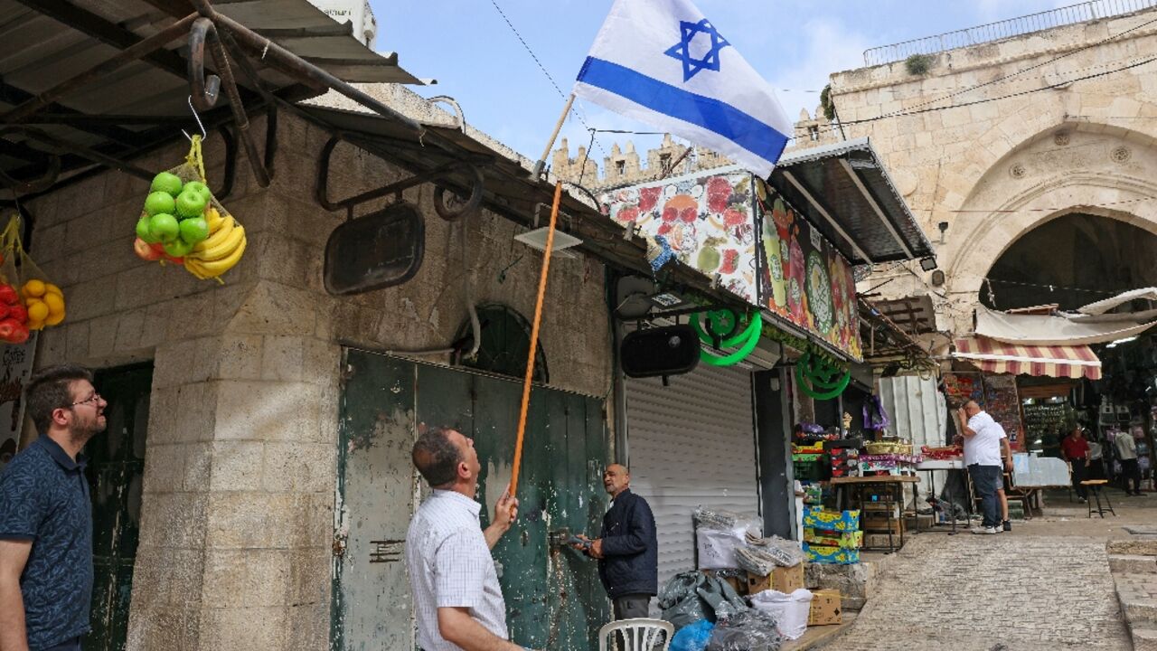 An Israeli flag is removed from above a Palestinian-owned shop in the wake of Jerusalem Day