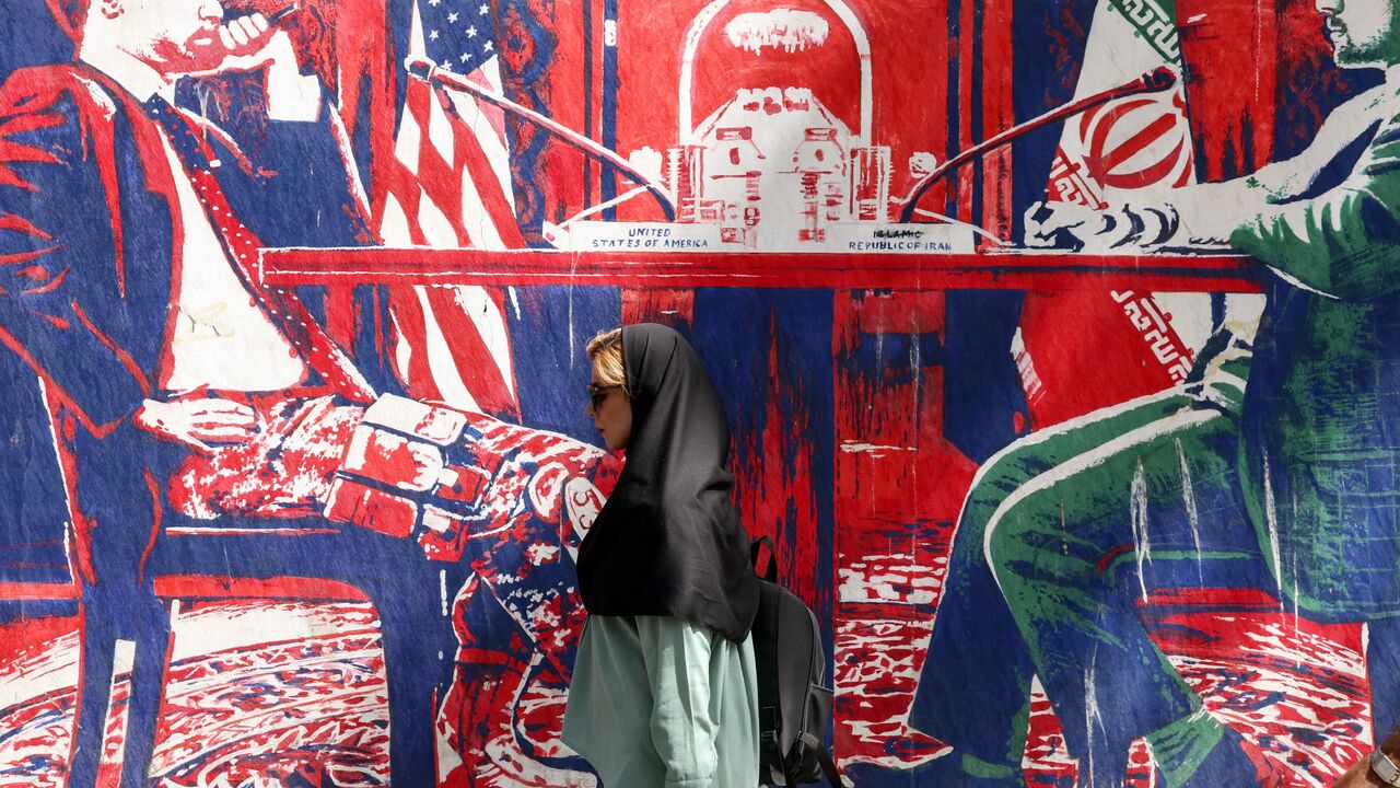 A woman walks past an anti-US mural near the former US Embassy in Tehran, on May 11, 2025.