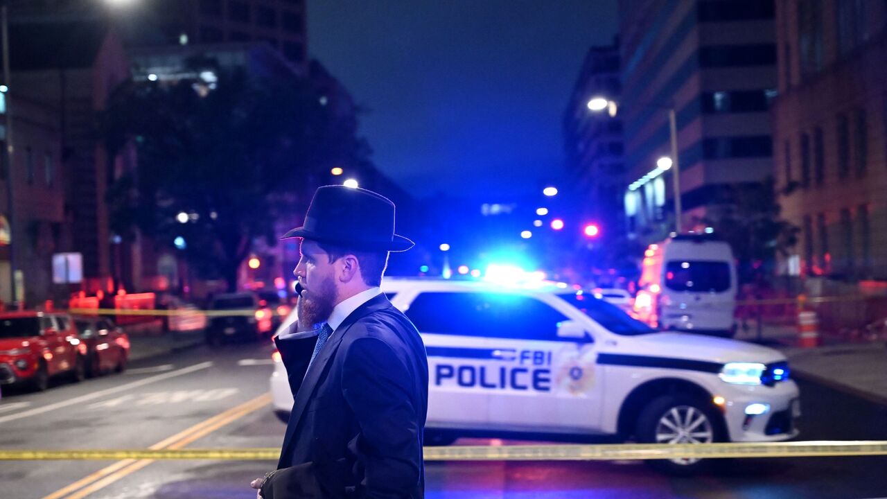 A man, standing behind police tape, talks on his cell phone outside the Capital Jewish Museum following a shooting that left two people dead, in Washington, DC, on May 21, 2025.