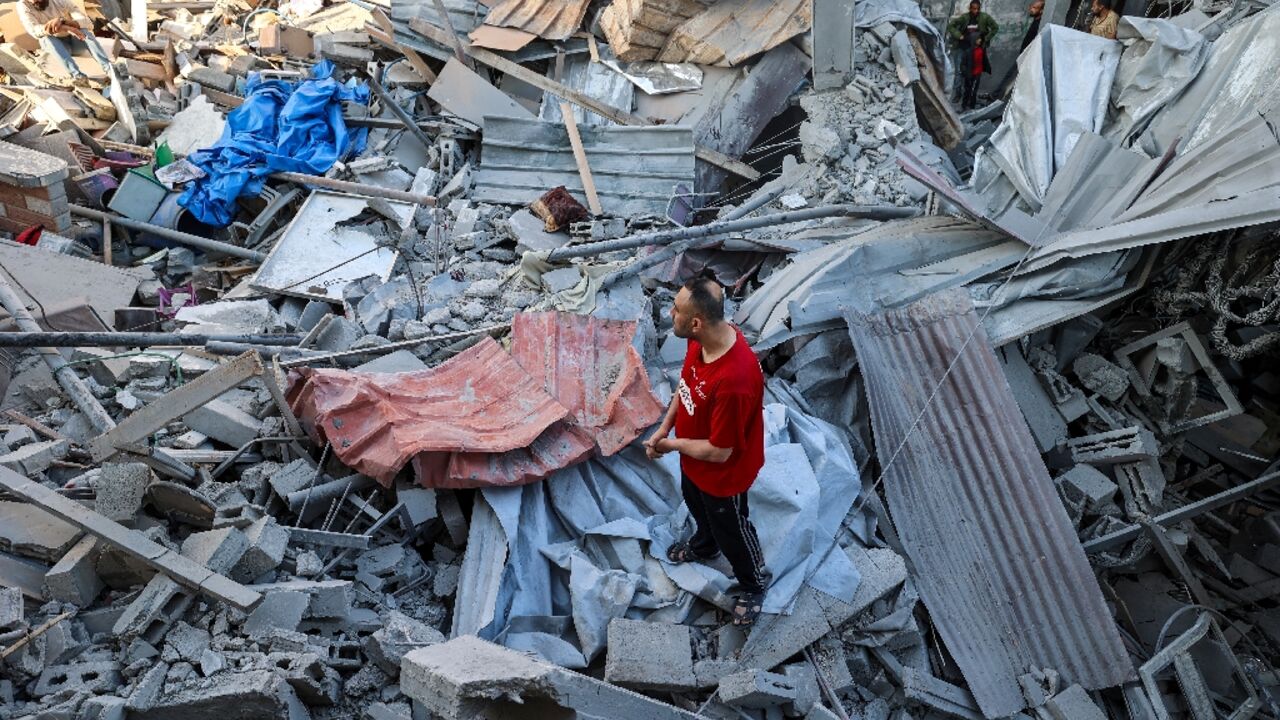 A man stands on the rubble of a building hit in an Israeli strike in the Bureij camp for Palestinian refugees in the central Gaza Strip 