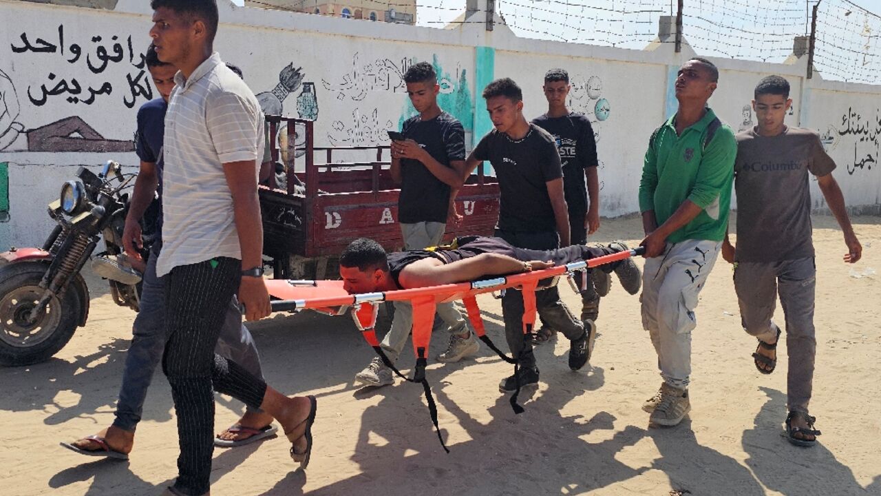 Palestinians carry a man towards a hospital in Rafah after he was wounded while queuing for aid