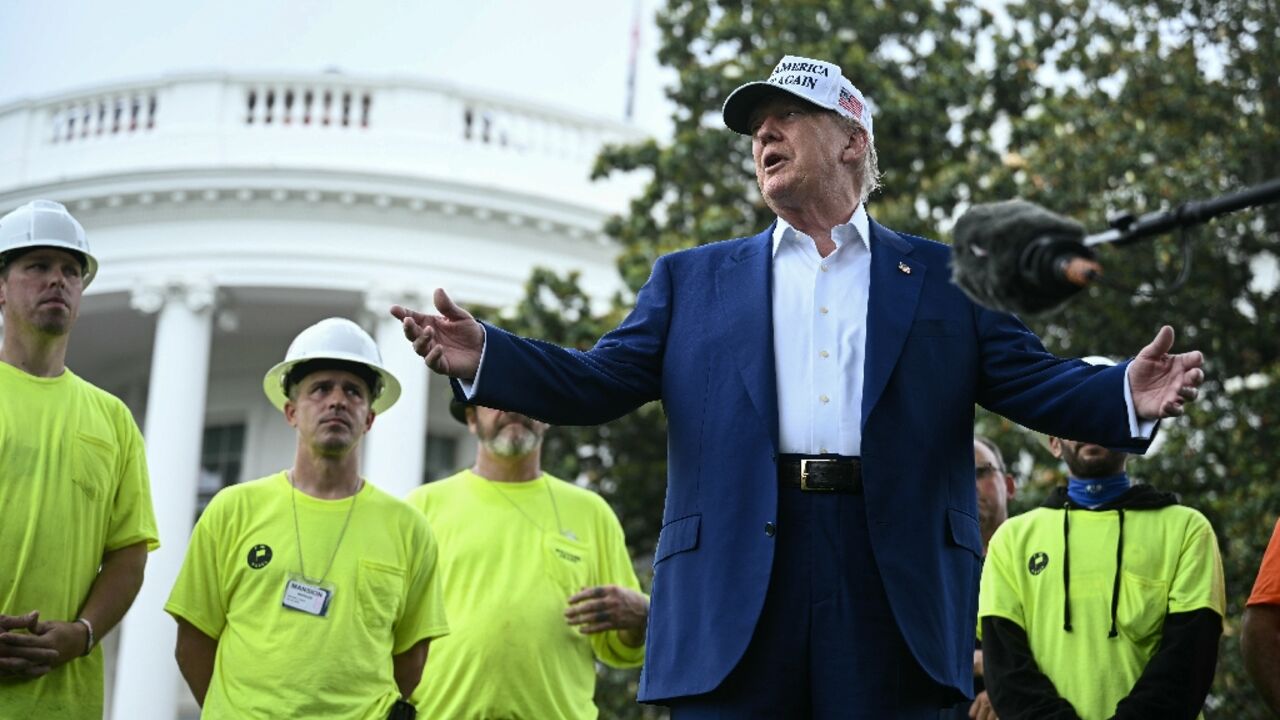 US President Donald Trump speaks to the press as workers install a large flag pole on the South Lawn of the White House in Washington, DC on June 18, 2025