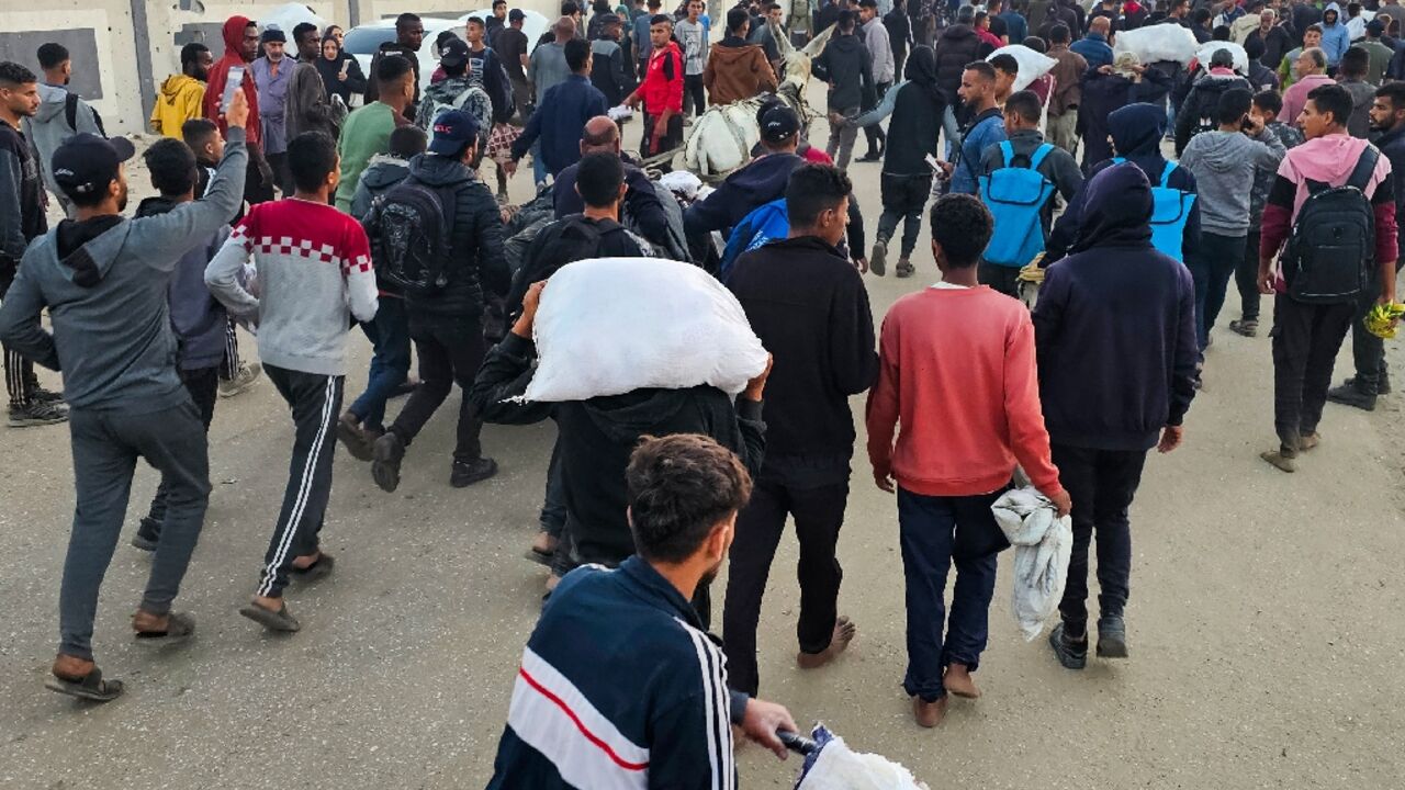 Displaced Palestinians, some carrying sacks of food, leave a distribution centre in Rafah, in the southern Gaza Strip