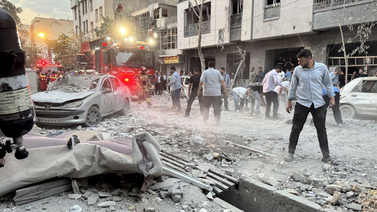 People and first-responders gather outside a building that was hit by an Israeli strike in Tehran on June 13, 2025.