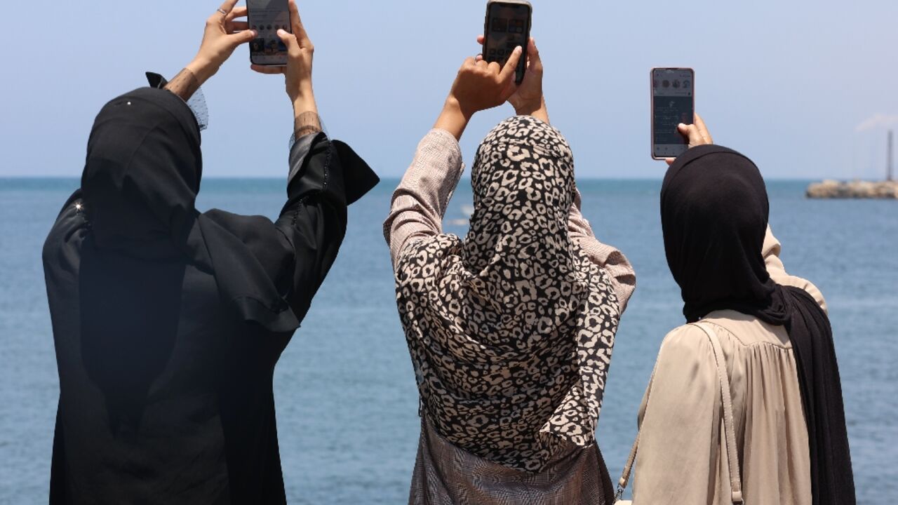 Palestinians raise their phones as they try to catch an internet signal in Gaza City