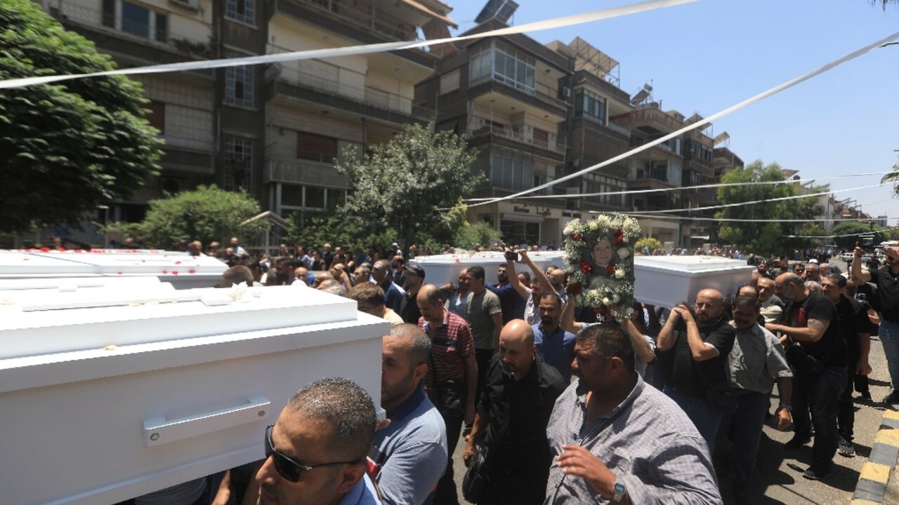 Mourners carry the coffins of some of the 25 people killed in a weekend church bombing in  Damascus in a procession through the Syrian capital's Al-Qassaa neighbourhood.
