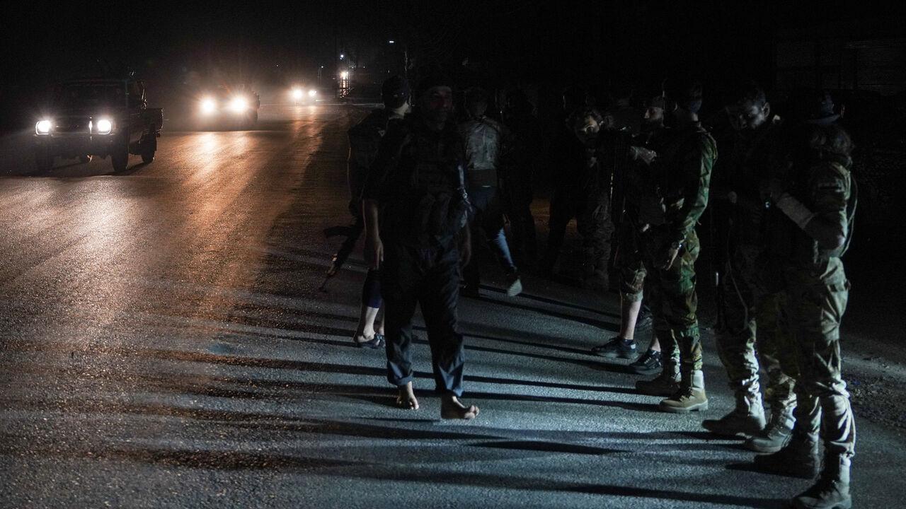 Members of Syrian security forces stand on the side of a road in Sweida countryside, as vehicles transporting other Syrian security forces make their way out of the predominantly druze city of Sweida, Syria, July 16, 2025. REUTERS/Karam al-Masri