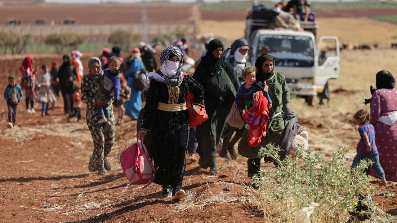 Women and children walk on land between Deraa and Sweida, after scores of people have been killed this week in violence in and around the predominantly Druze city of Sweida, pitting fighters from the Druze minority against government security forces and members of Bedouin tribes, in Deraa, Syria July 17, 2025. REUTERS/Khalil Ashawi