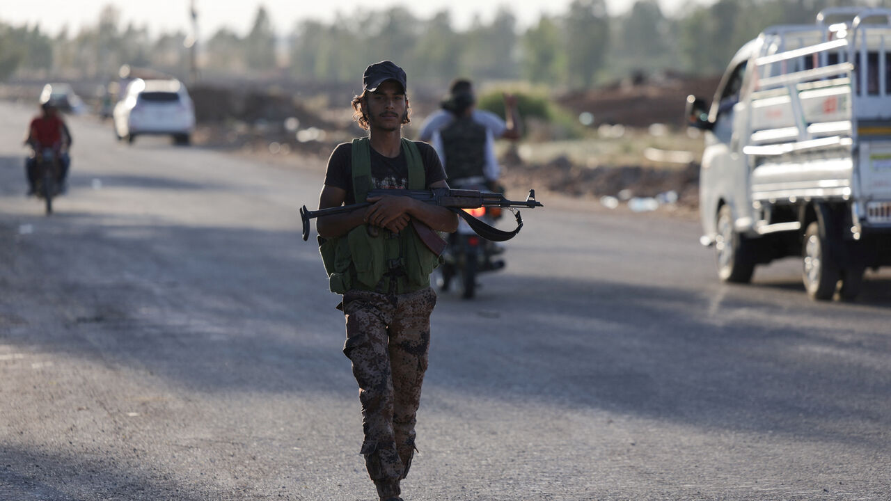 An armed Syrian Bedouin fighter walks along a road, as they launch a new offensive in Syria's Sweida province against Druze fighters, a Bedouin military commander told Reuters on Thursday, despite a truce that had been announced the previous evening to end days of bloody fighting, in Deraa, Syria July 17, 2025. REUTERS/Khalil Ashawi