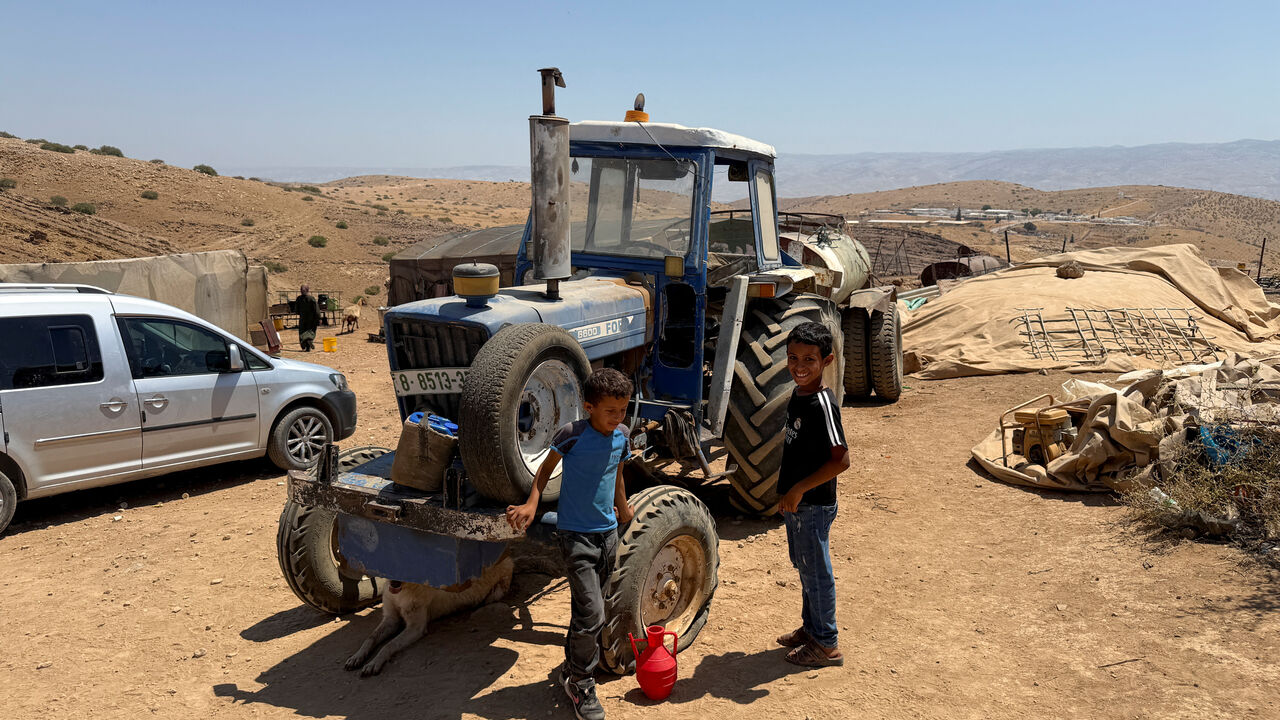 Palestinian Bedouin youth stand in front of a tractor in a community in the Jordan valley, in the Israeli-occupied West Bank, July 18, 2025. REUTERS/Ali Sawafta