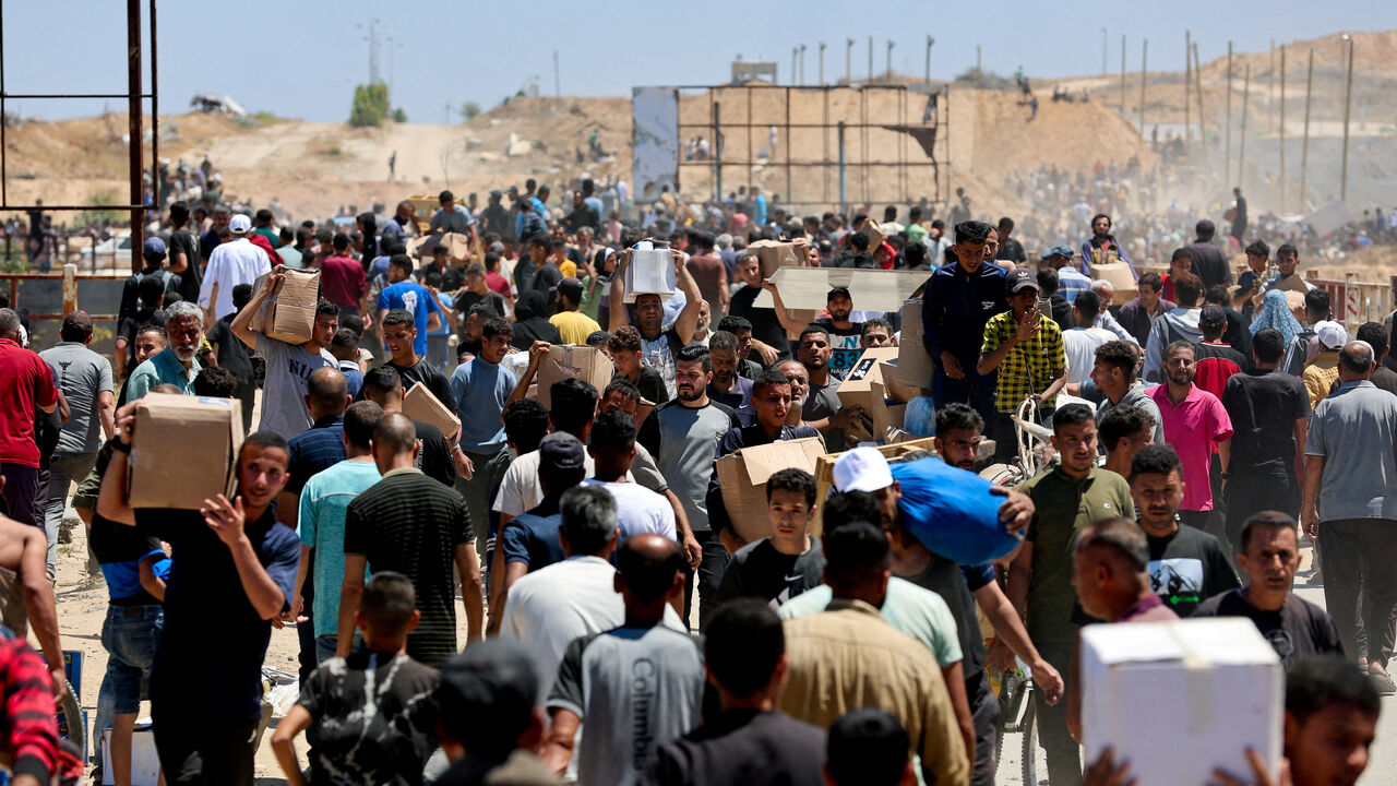 FILE PHOTO: Palestinians carry aid supplies which they received from the U.S.-backed Gaza Humanitarian Foundation, in the central Gaza Strip, May 29, 2025. REUTERS/Ramadan Abed/File Photo