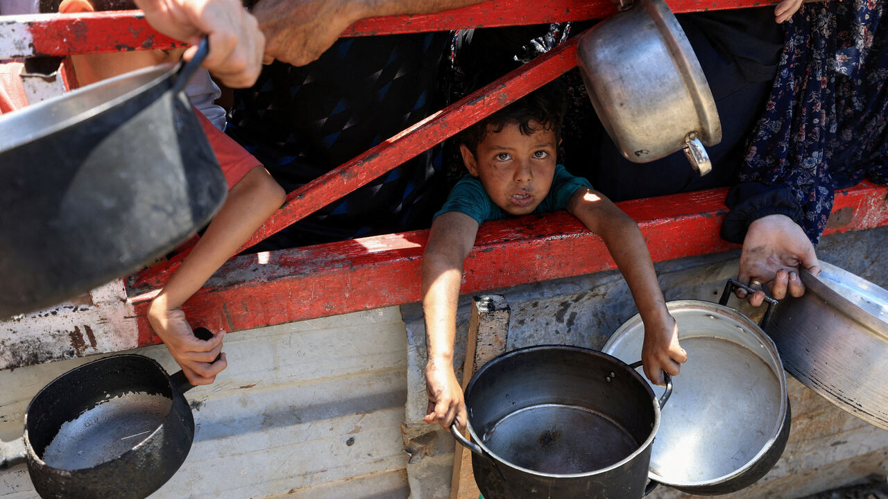 A child holds a pot as Palestinians gather to receive food from a charity kitchen, amid a hunger crisis, in Gaza City, July 22, 2025. REUTERS/Dawoud Abu Alkas