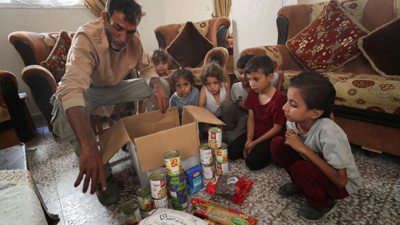 Fares Zaher, a Palestinian father of eight, displays the contents of an airdropped food parcel he received, in Gaza City, July 28, 2025. REUTERS/Mahmoud Issa