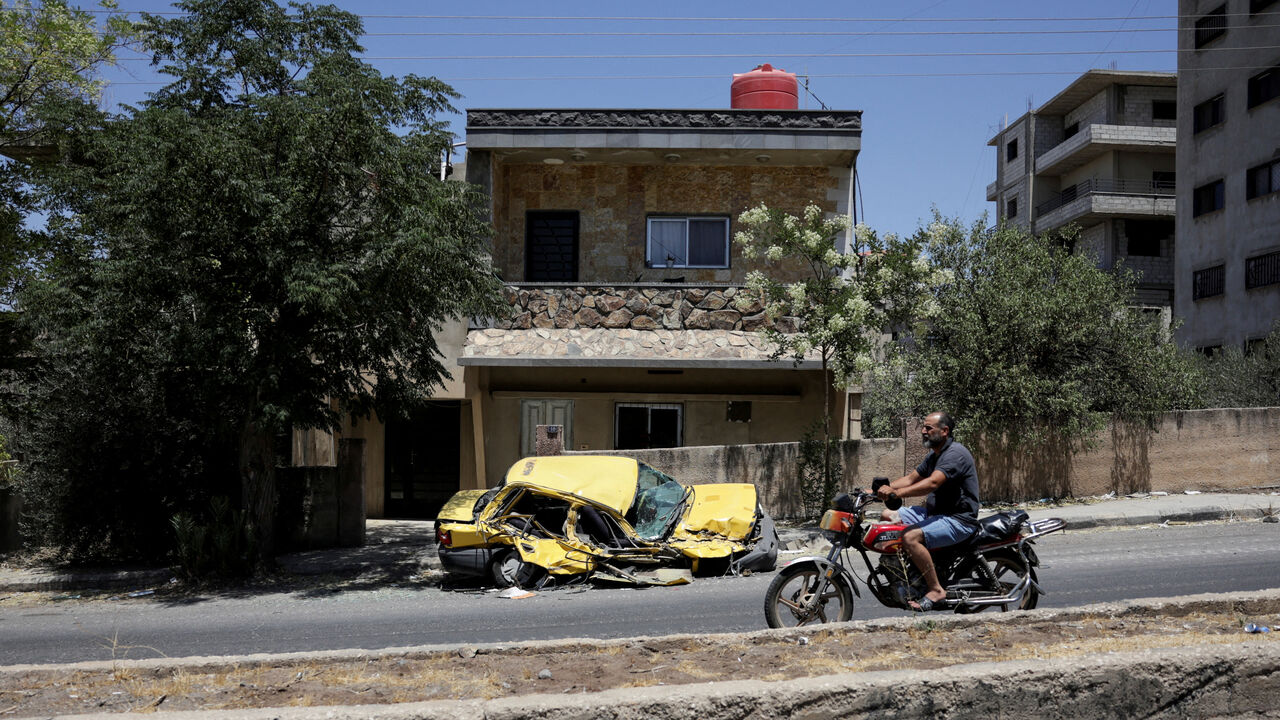 A man rides a motorcycle past a destroyed car, following deadly clashes between Druze fighters, Sunni Bedouin tribes and government forces, in Syria's predominantly Druze city of Sweida, Syria July 25, 2025. REUTERS/Khalil Ashawi/File Photo